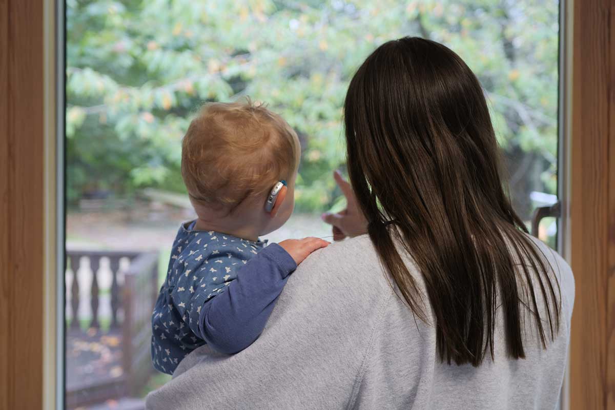 An adult holding a deaf toddler at The Elizabeth Foundation